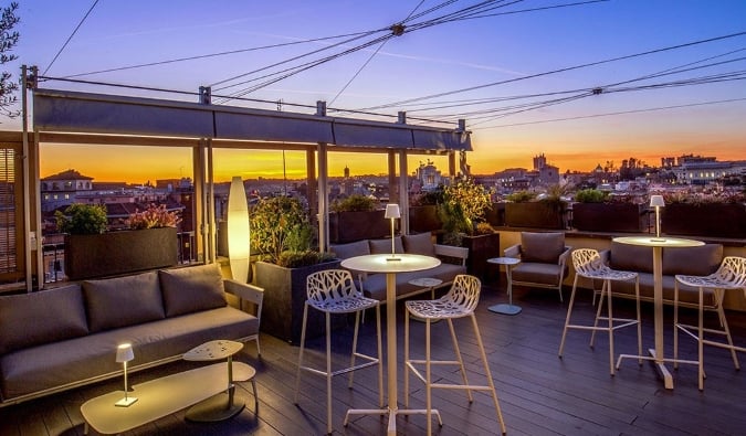 Bar e lounge na cobertura com a paisagem urbana ao fundo logo após o pôr do sol no Monti Palace Hotel em Roma, Itália